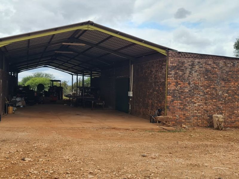 Large open-sided farm shed featuring a sturdy brick structure and corrugated metal roofing, suitable for agricultural storage or machinery housing.