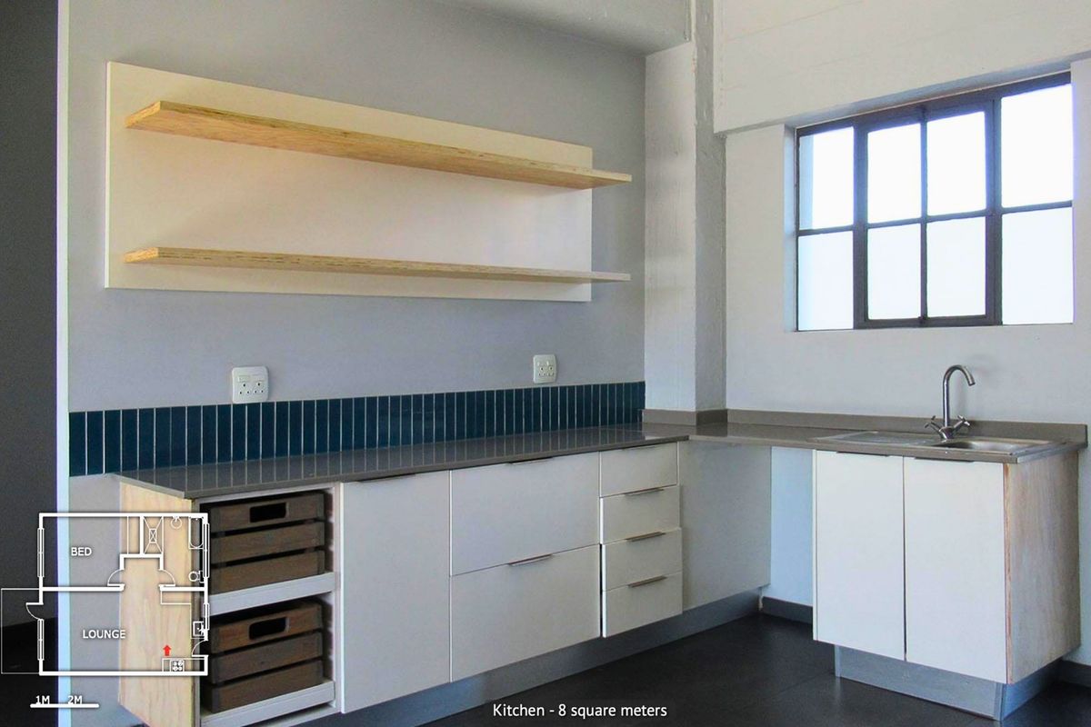 Modern kitchen featuring clean white cabinetry, stone countertops, tiled splashback, and floating shelves, complemented by an industrial-style window.