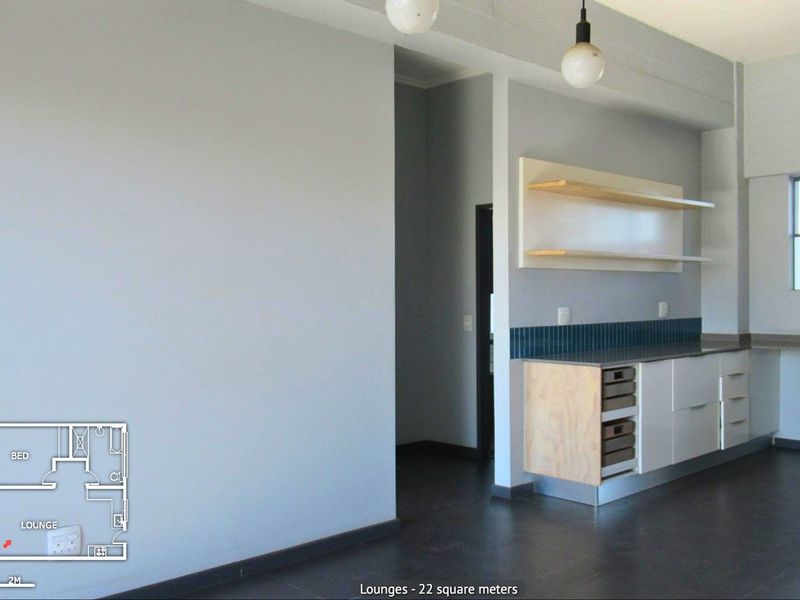 An open-plan living area featuring modern built-in cabinetry, floating shelves, a tiled backsplash, and dark flooring, providing a clean and versatile space.