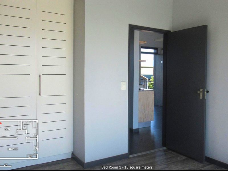 A clean, empty bedroom featuring built-in wardrobes, modern laminate flooring, and a neutral color palette, offering a versatile space for personalization.