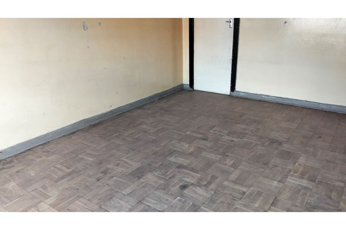 An empty bedroom featuring worn parquet flooring and painted walls, presenting a blank canvas for renovation and interior design updates.