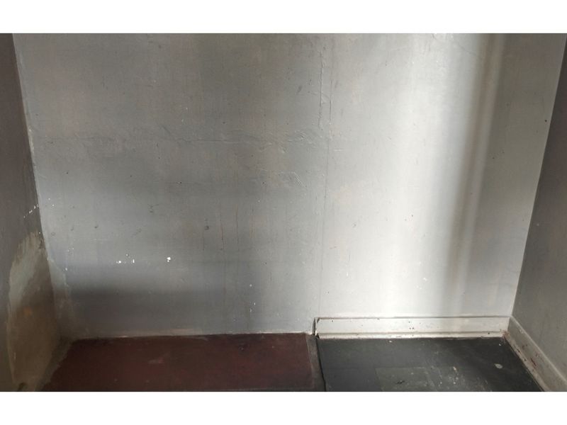 A small, unfinished interior space showing significant wear to the wall surfaces and flooring.