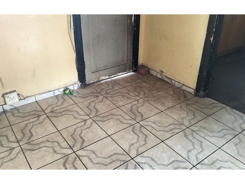 An empty entry area featuring patterned floor tiles, requiring cosmetic updates to the walls and door frames to improve the overall condition.