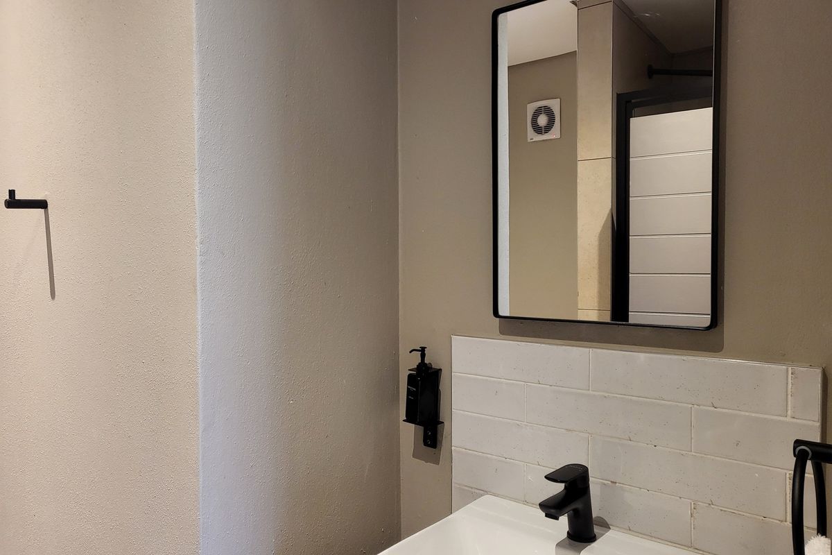 A modern bathroom vanity area featuring a white basin, matte black faucet, subway tile backsplash, and a framed mirror.