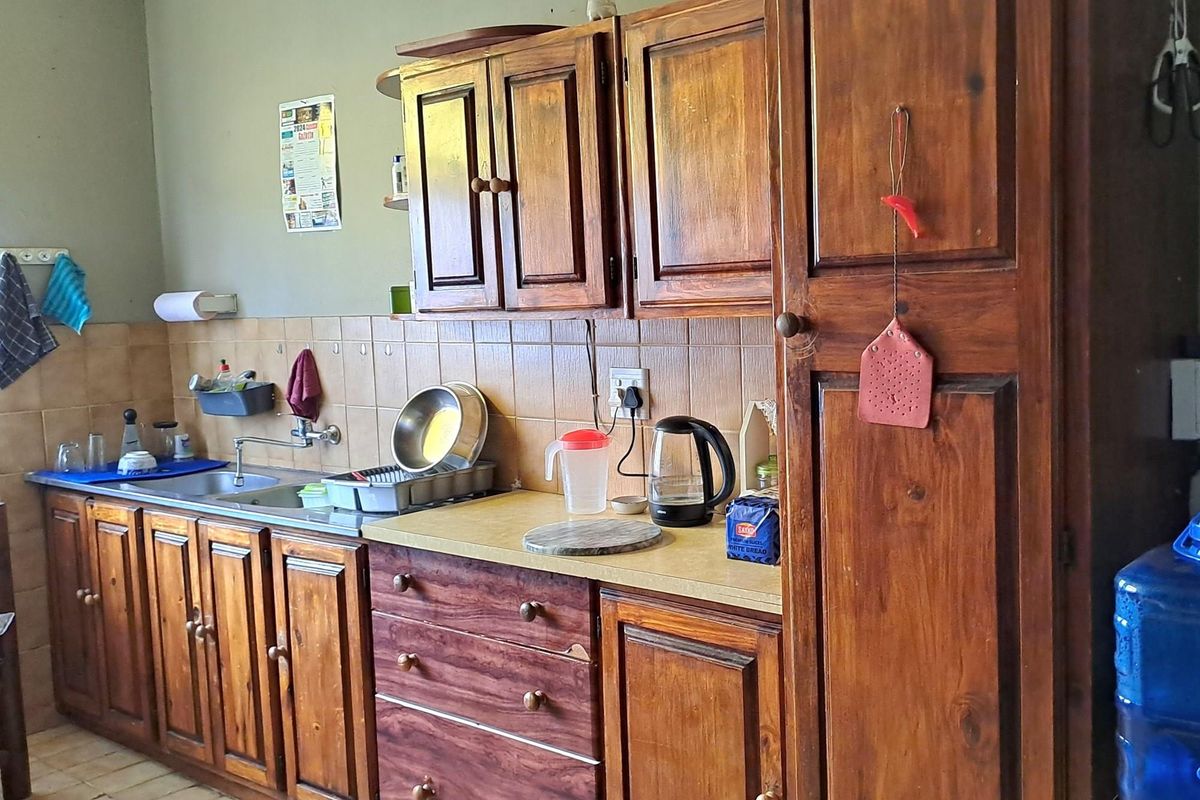 A functional kitchen featuring traditional timber cabinetry, a tiled backsplash, and a stainless steel sink with integrated plumbing fixtures.
