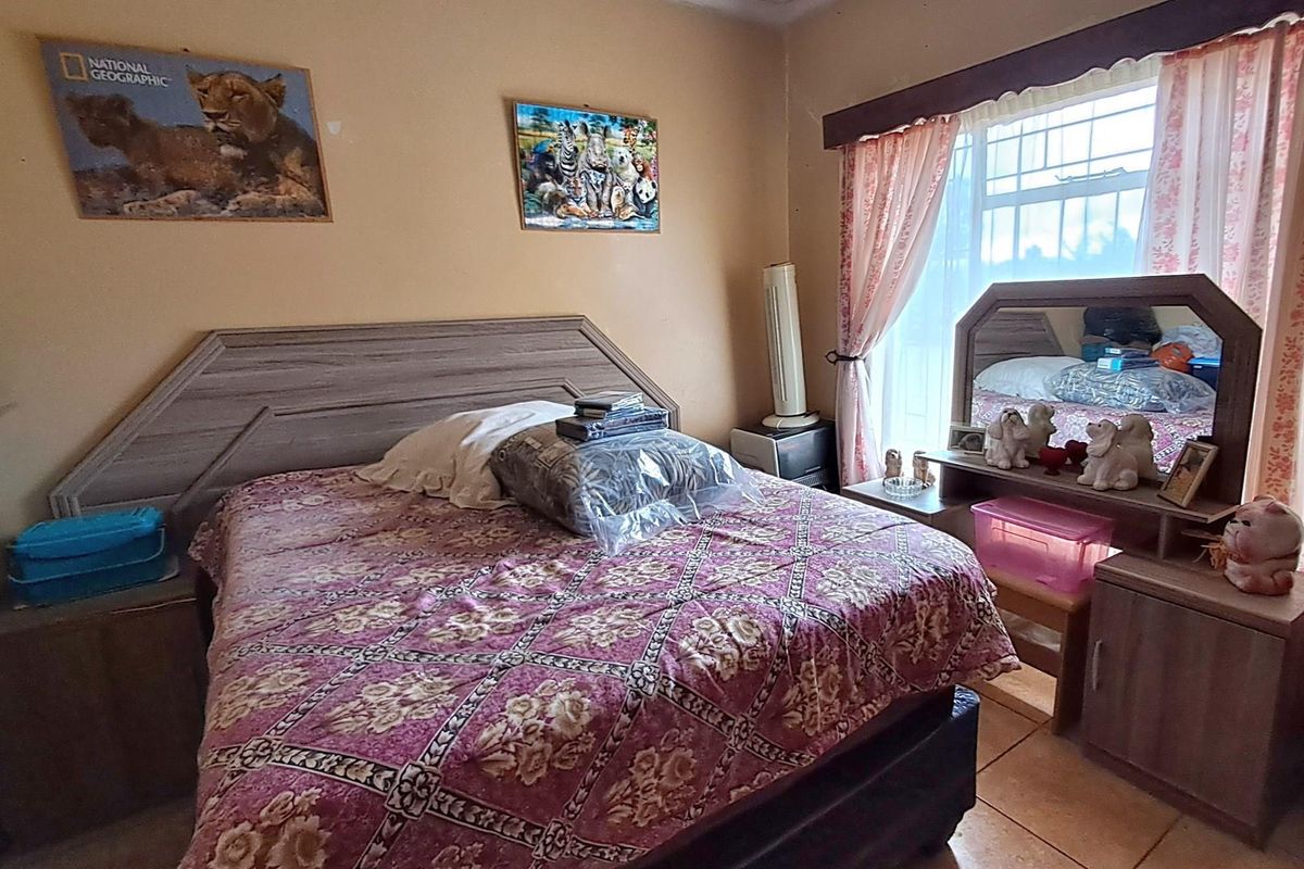 A bedroom featuring tiled flooring and a large window with curtains, providing a functional space for rest.
