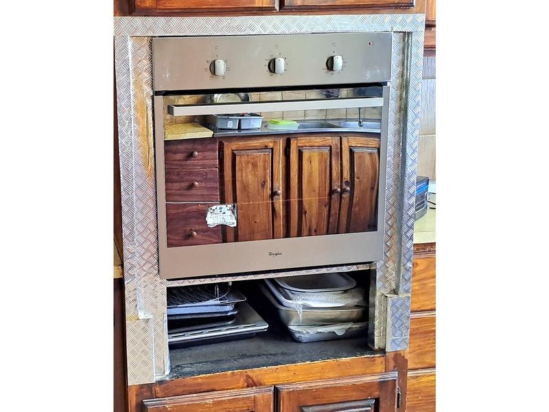 Built-in oven unit featuring a stainless steel finish, integrated into wooden cabinetry with a custom metal trim surround.