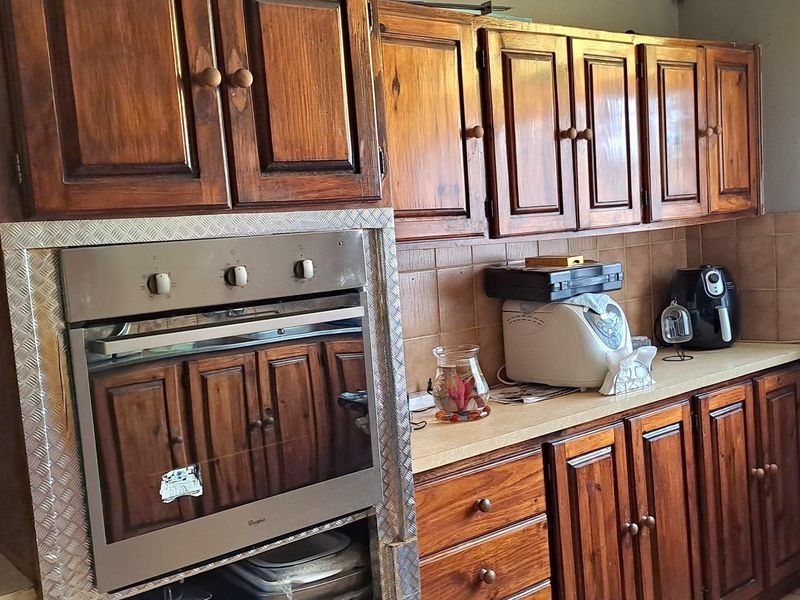 A dated kitchen featuring traditional dark wood cabinetry, a built-in oven, and tiled backsplash, offering potential for a modern renovation.