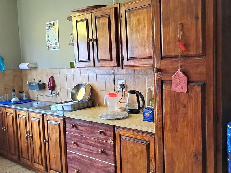 A functional kitchen featuring traditional timber cabinetry, a tiled backsplash, and a stainless steel sink with integrated plumbing fixtures.