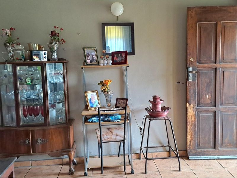 Interior view of a living area featuring tiled flooring and a traditional timber door with visible wear.