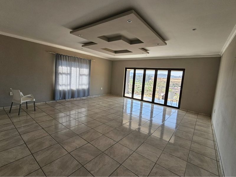 Spacious living area featuring tiled floors, a modern recessed ceiling with downlights, and large sliding glass doors leading to an outdoor view.