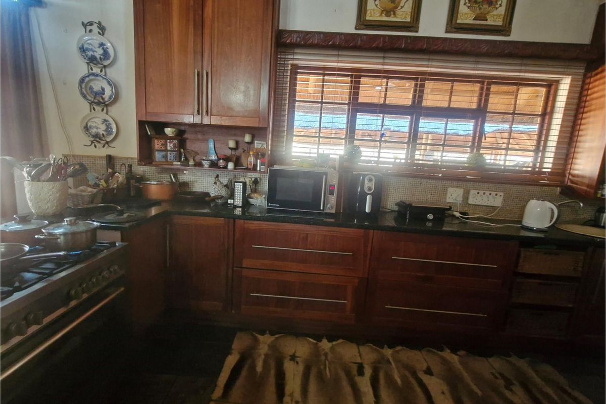 A functional kitchen featuring warm wooden cabinetry, granite countertops, a gas stove, and a tiled backsplash with natural light from the window.