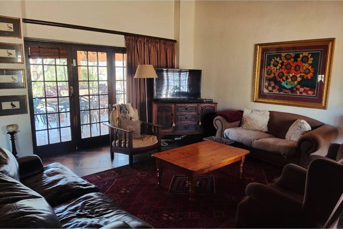 A comfortable living room featuring terracotta floor tiles and large timber-framed glass doors providing direct access to the outdoor patio area.