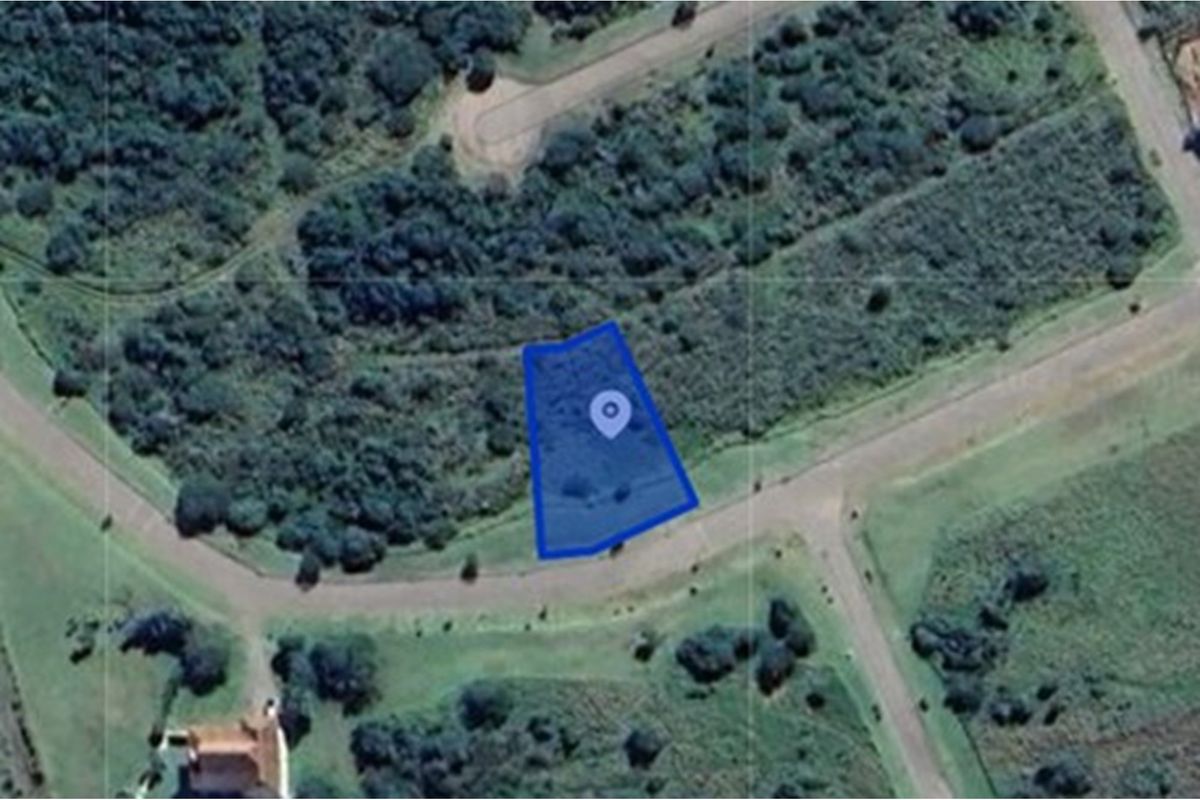Aerial view of a vacant residential plot highlighted in blue, situated within a landscaped estate with surrounding vegetation and road access.
