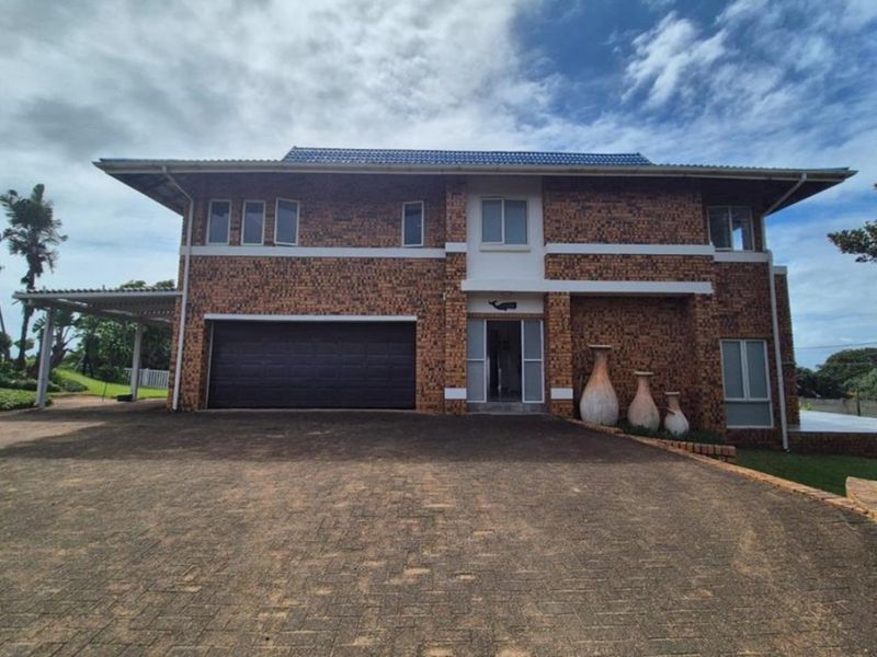 A two-story face brick house featuring a paved driveway, double garage, and covered carport area.