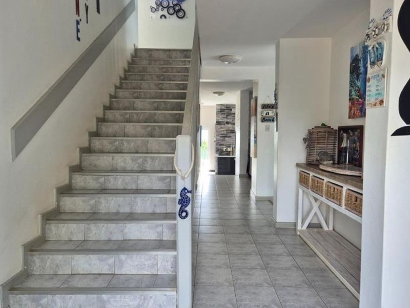 A bright entrance hallway featuring tiled flooring and a staircase leading to the upper level, providing access to the main living areas.
