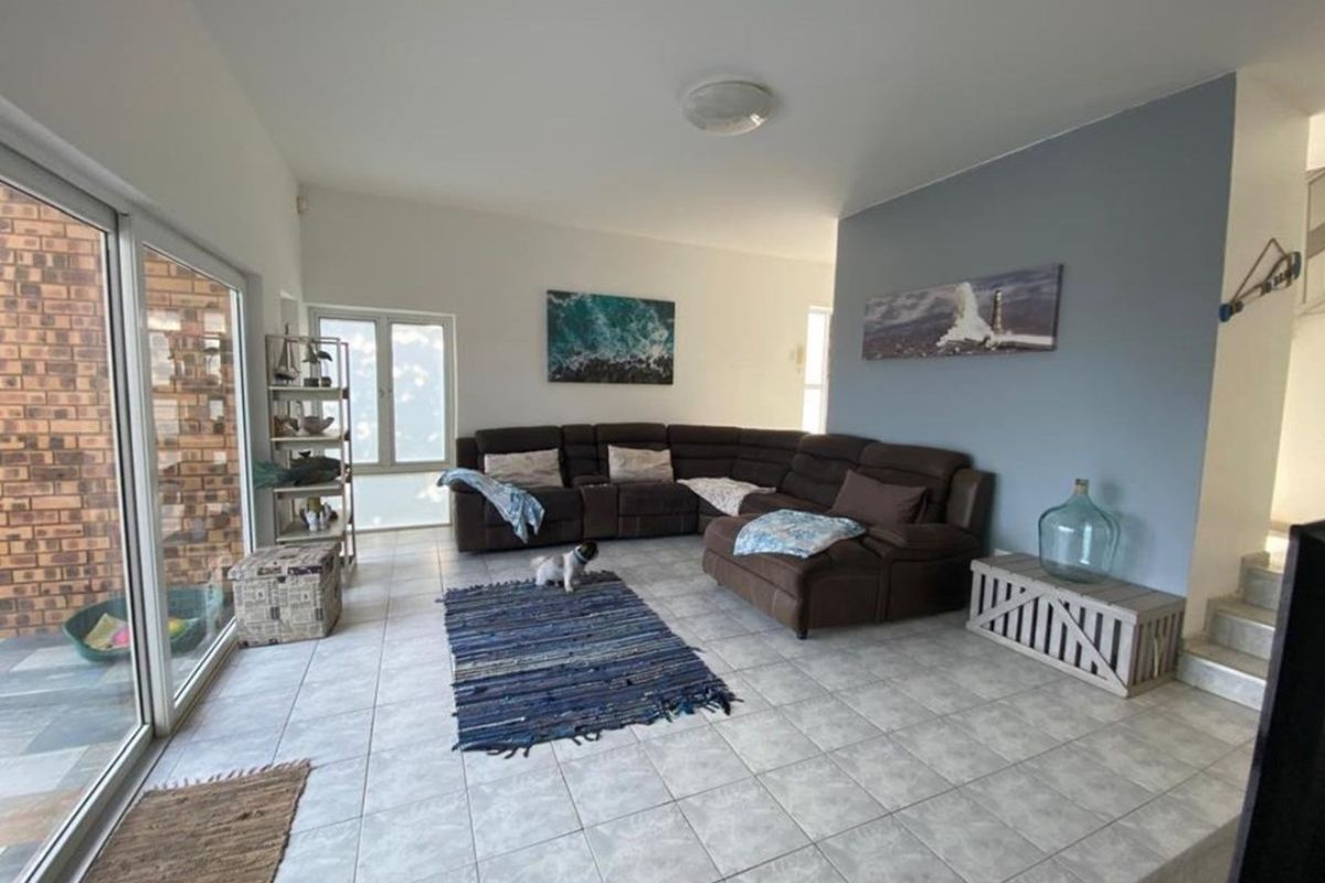 Spacious living room featuring neutral tiled flooring and large sliding glass doors providing ample natural light and access to the exterior.