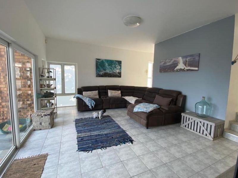 Spacious living room featuring neutral tiled flooring and large sliding glass doors providing ample natural light and access to the exterior.