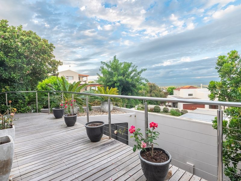 An elevated timber balcony featuring a stainless steel and wire cable balustrade, offering expansive views of the surrounding neighbourhood.