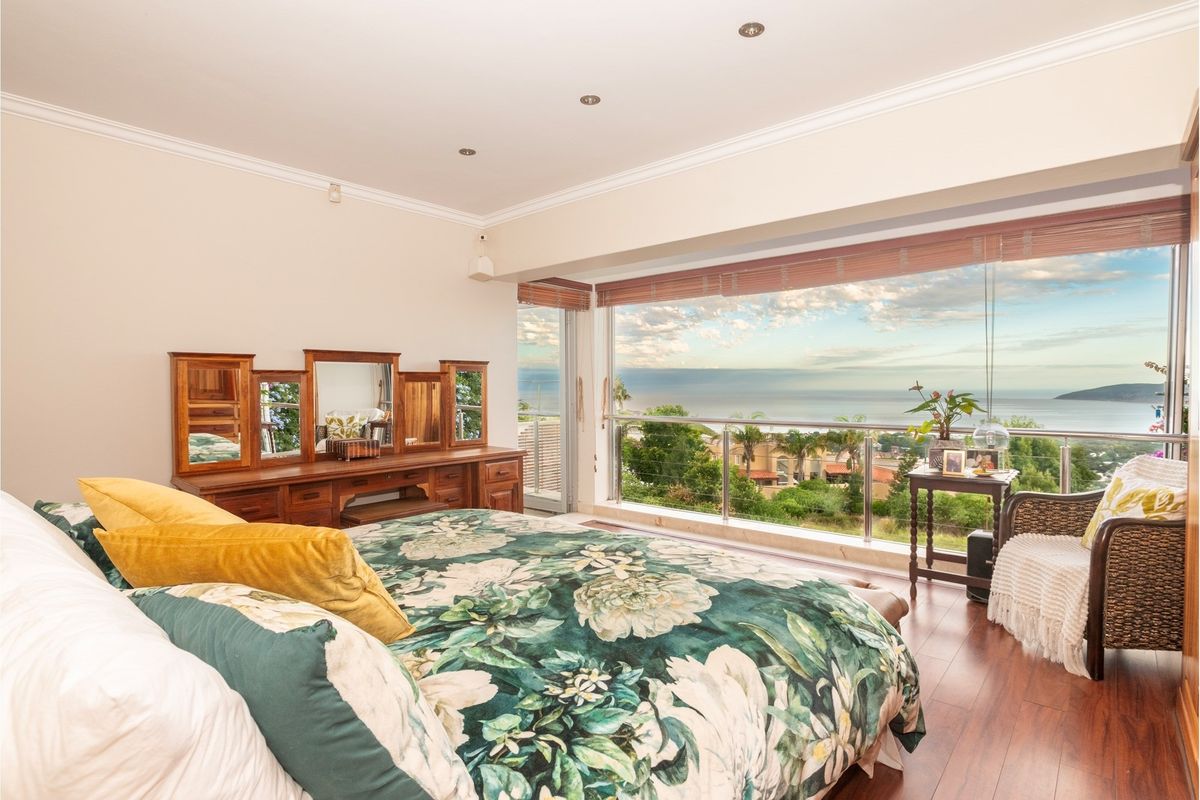 Spacious bedroom featuring laminate flooring, recessed lighting, and expansive sliding glass doors opening to a balcony with panoramic ocean and coastal views.