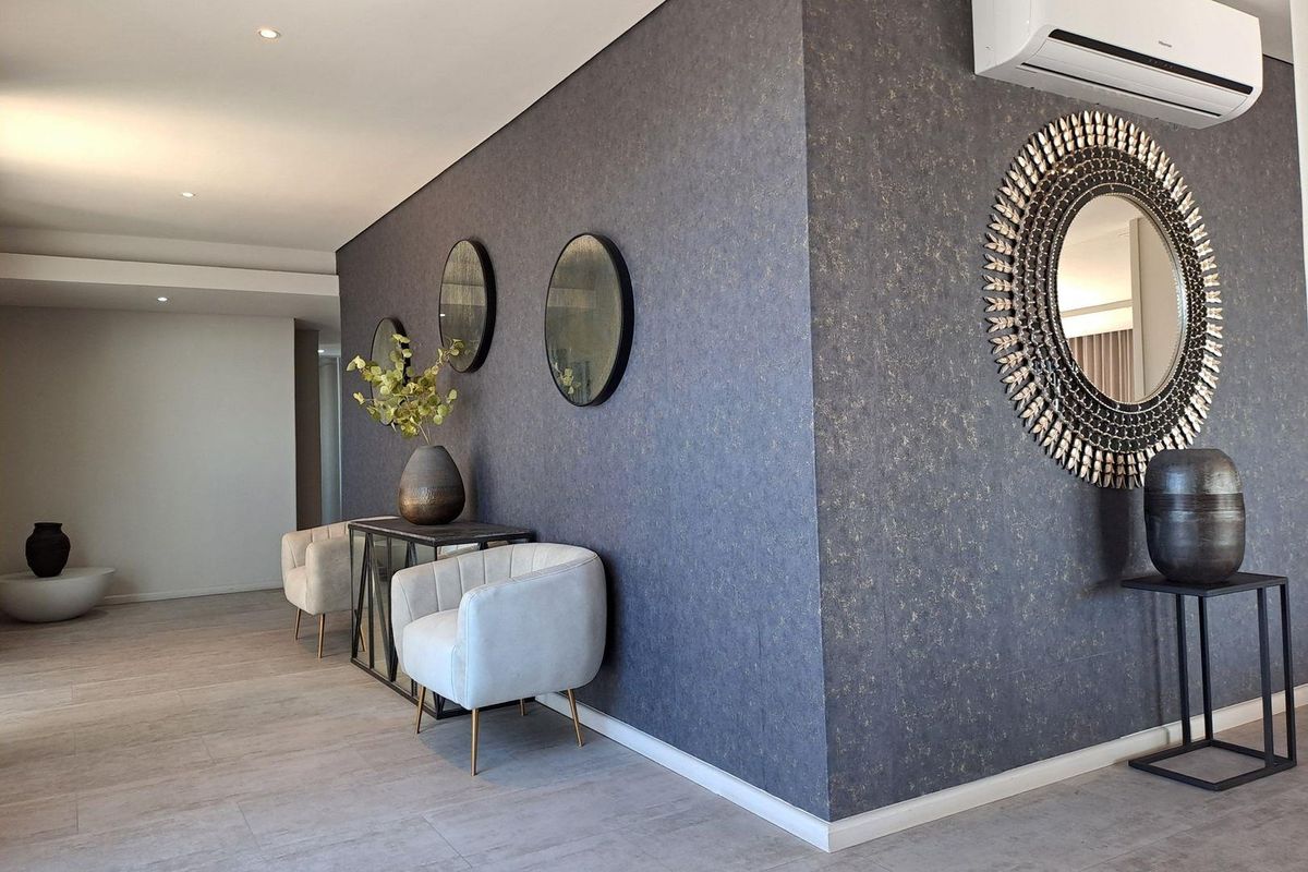 A modern living area featuring textured feature walls, tiled flooring, recessed lighting, and a wall-mounted split-system air conditioning unit.