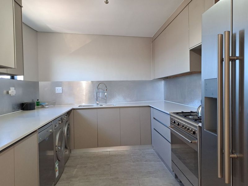 Modern kitchen featuring sleek cabinetry, stone countertops, stainless steel splashback, and integrated gas cooking facilities with ample workspace.