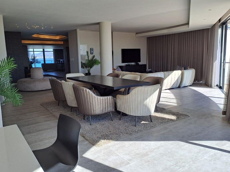 Spacious open-plan living and dining area featuring modern tiled flooring, recessed ceiling lighting, and large sliding glass doors leading to an outdoor space.