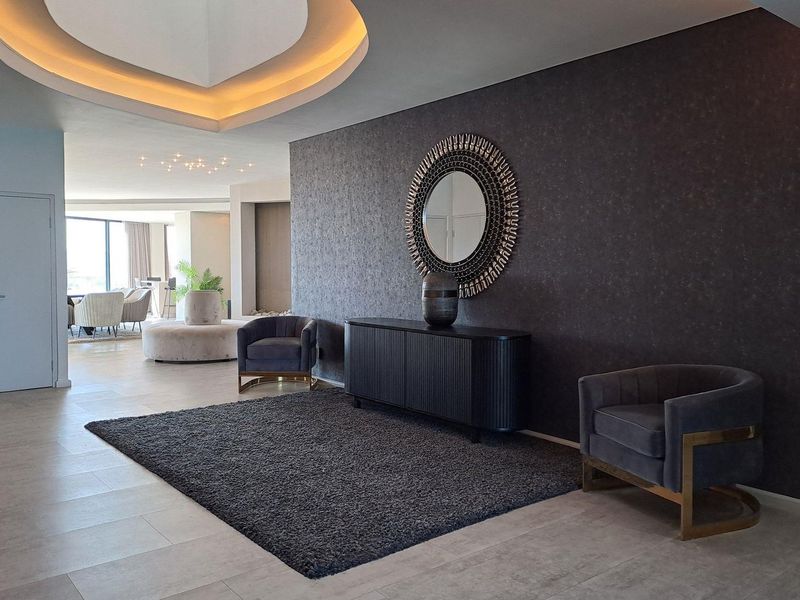 Spacious modern entrance foyer featuring elegant recessed cove lighting, high-quality tiled flooring, and a sophisticated dark feature wall.