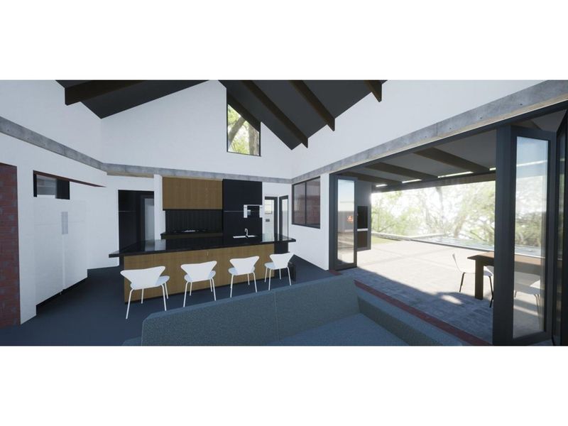 A modern open-plan living and kitchen area featuring vaulted ceilings, exposed beams, and large folding doors opening to an outdoor patio space.