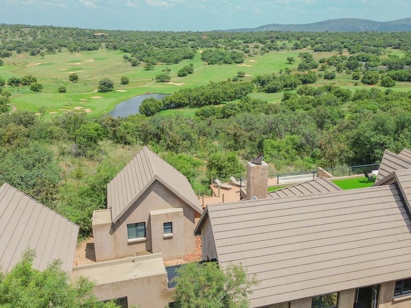 Aerial view of the property showcasing the roof structure, chimney, and outdoor deck area overlooking the surrounding golf course landscape.