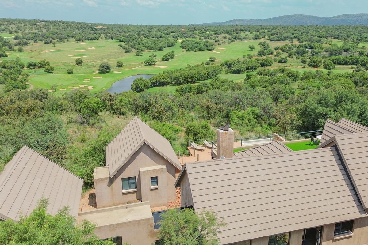 Aerial view of the property showcasing the roof structure, chimney, and outdoor deck area overlooking the surrounding golf course landscape.