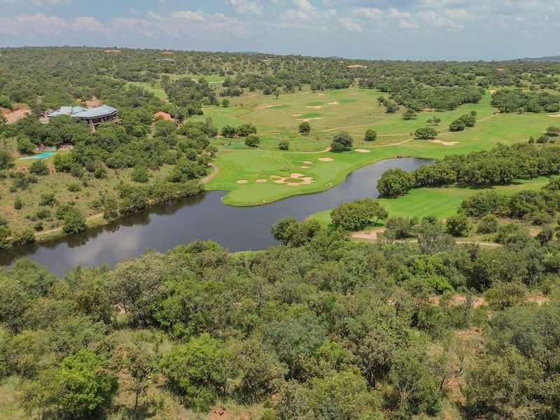 An aerial view of the property showcasing the surrounding golf course, natural landscape, and water features.