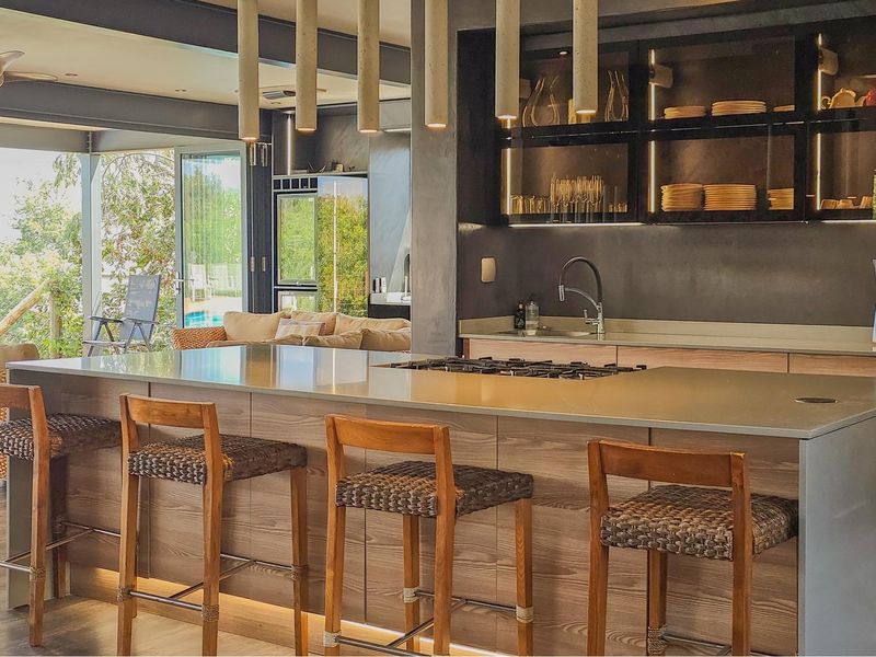 Modern open-plan kitchen featuring a large island with integrated gas cooktop, sleek cabinetry, and seamless flow to the outdoor patio area.