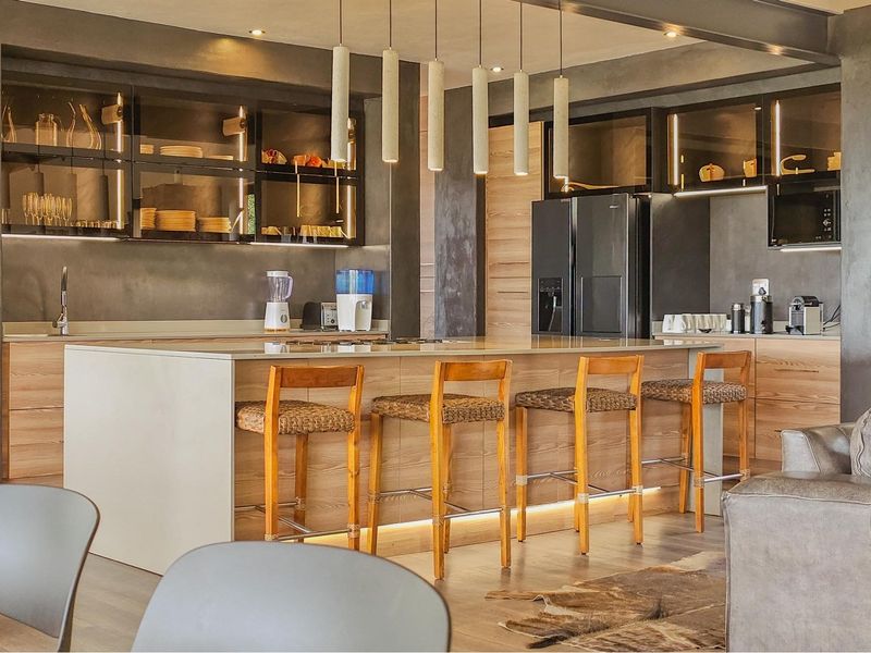 Modern open-plan kitchen featuring a large central island, sleek cabinetry, integrated appliances, and stylish pendant lighting, creating a sophisticated and functional living space.