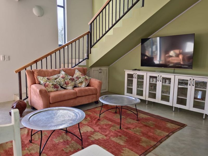 Living area featuring a staircase with a metal balustrade and built-in under-stair storage, set against a painted feature wall.