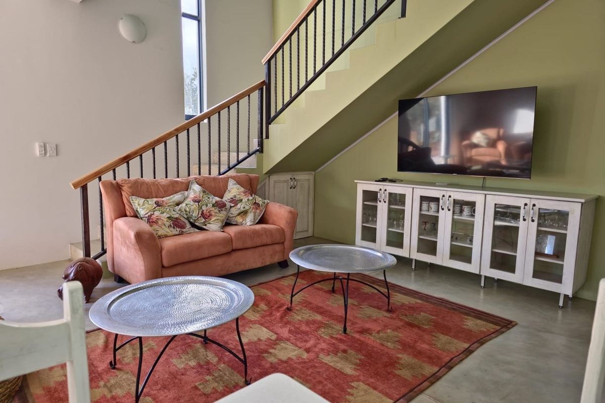 Living area featuring a staircase with a metal balustrade and built-in under-stair storage, set against a painted feature wall.