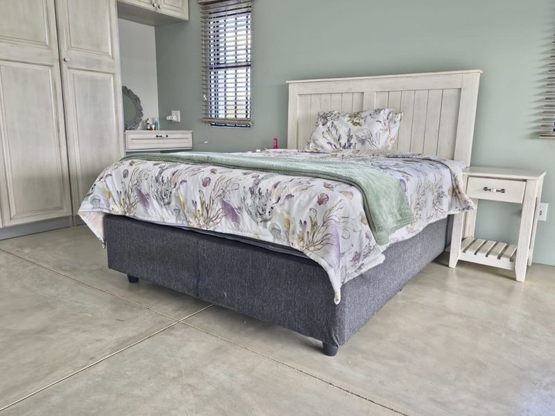 A well-maintained bedroom featuring polished concrete flooring, built-in cabinetry, and venetian blinds.