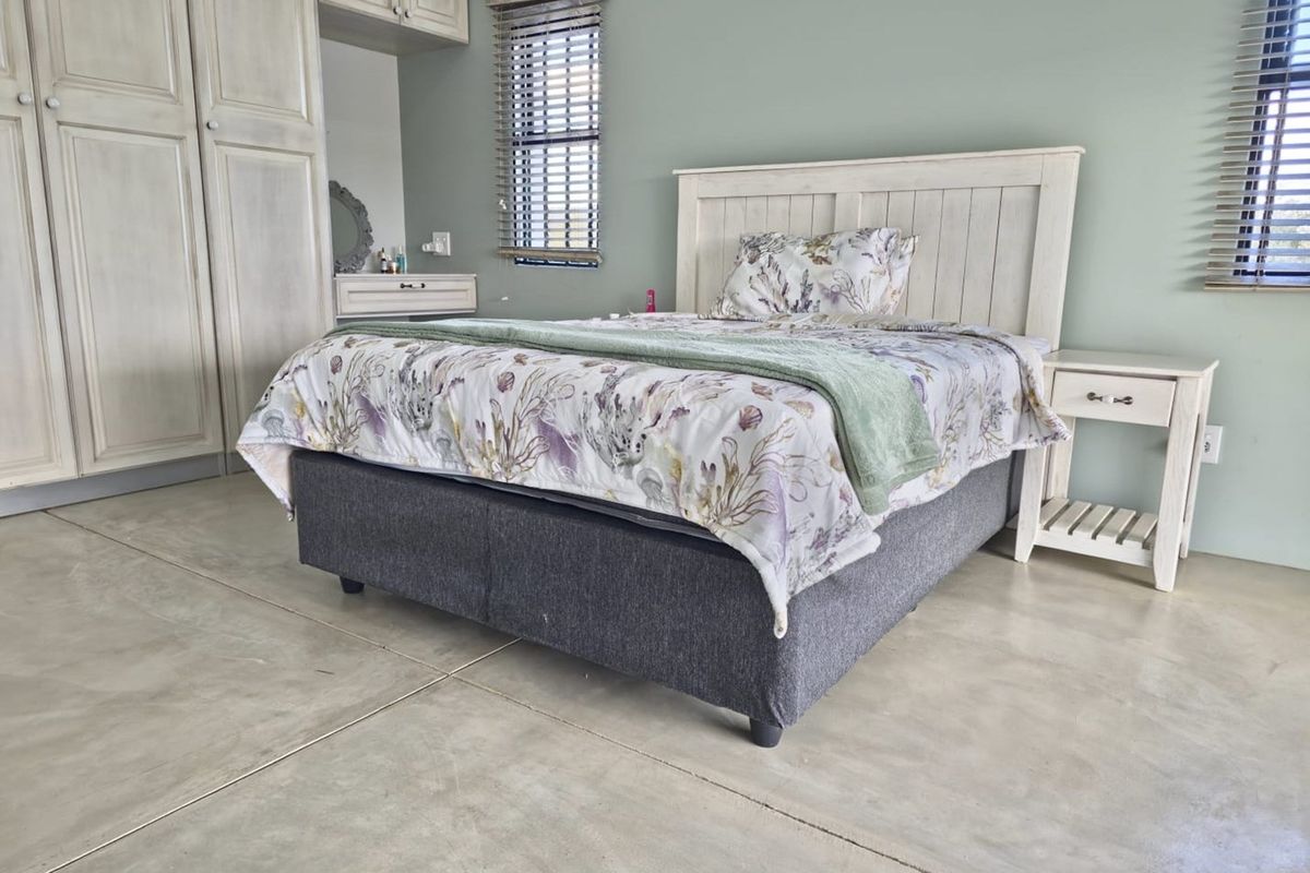 A well-maintained bedroom featuring polished concrete flooring, built-in cabinetry, and venetian blinds.