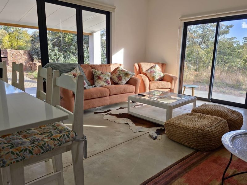 Bright open-plan living area featuring polished concrete floors and large sliding glass doors providing seamless access to the outdoor patio and natural surroundings.