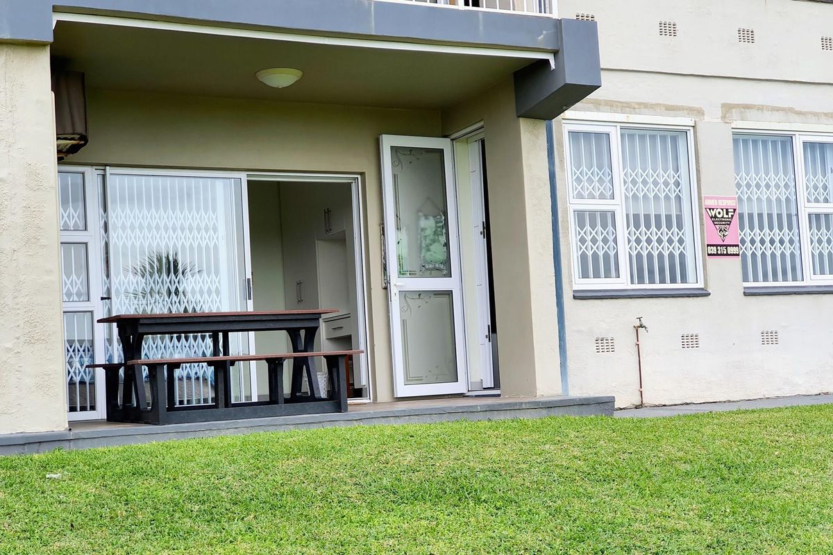 Ground floor apartment patio area featuring a covered terrace, sliding glass doors, security gates, and direct access to a communal garden space.