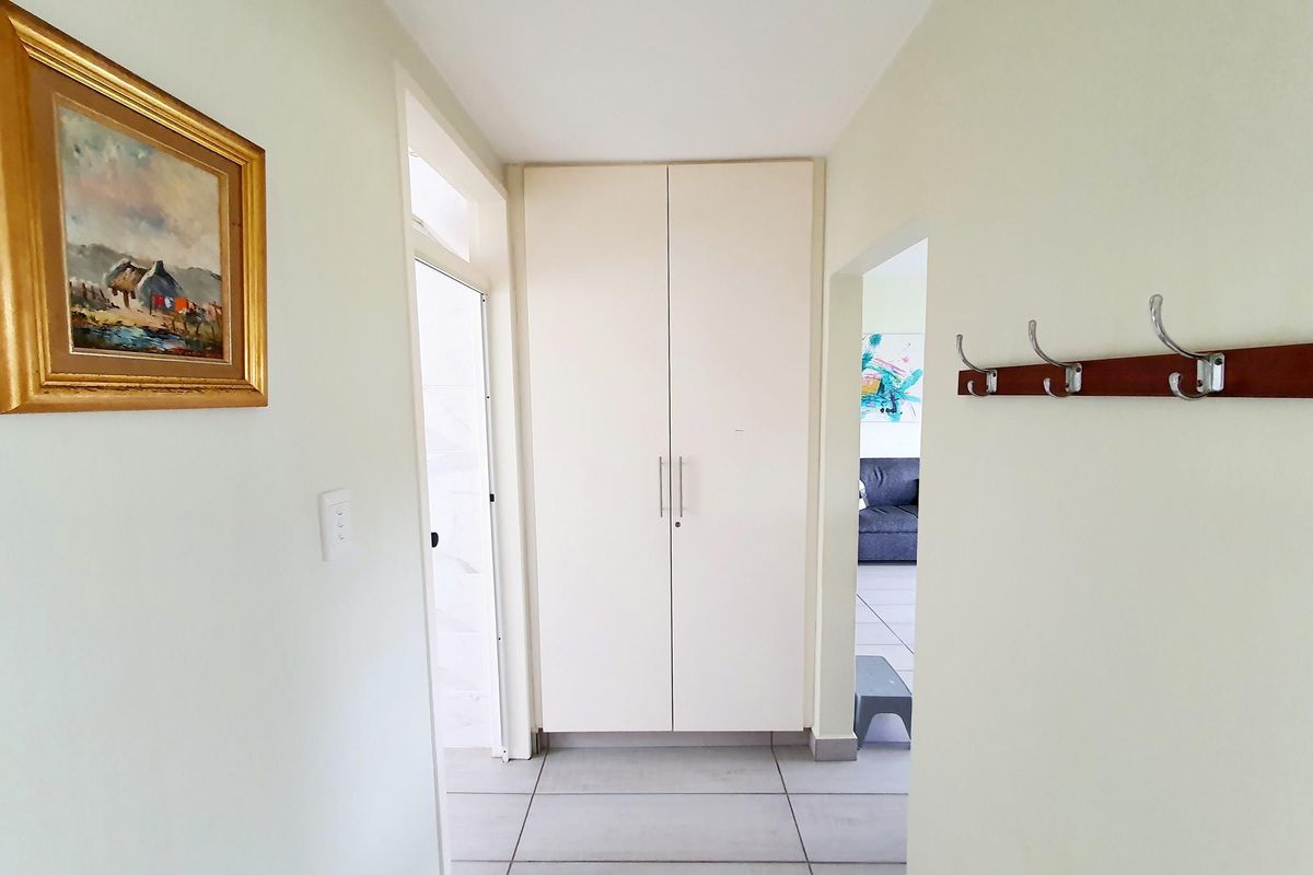 A functional hallway featuring built-in storage cabinetry and tiled flooring, providing access to adjacent rooms within the apartment.