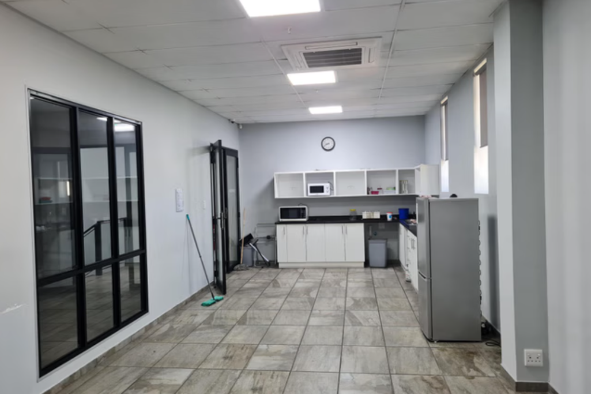 Functional industrial kitchen area featuring built-in cabinetry, tiled flooring, recessed ceiling lighting, and integrated air conditioning unit.
