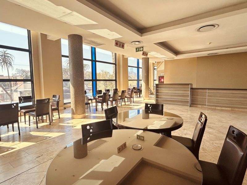 Spacious open-plan retail or dining area featuring large floor-to-ceiling windows, tiled flooring, recessed ceiling lighting, and structural support columns.