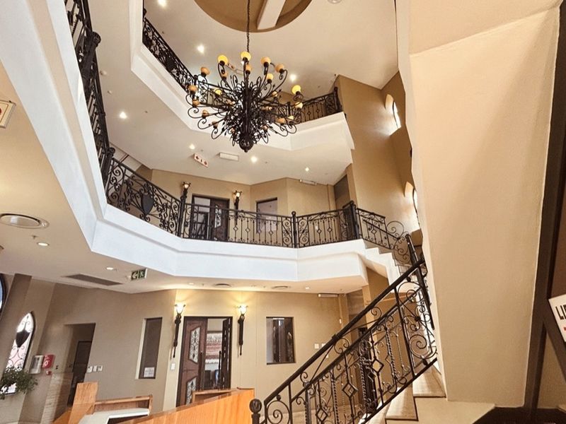 Grand multi-level atrium featuring ornate wrought iron railings, a decorative chandelier, and integrated lift access within a professional retail or commercial building.