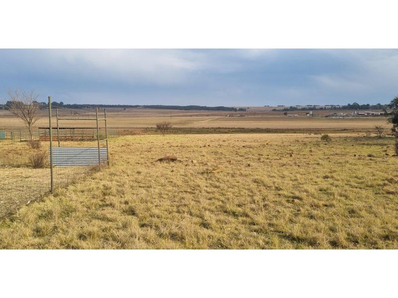 Expansive rural landscape view featuring open grazing land and perimeter wire fencing on a farm property.