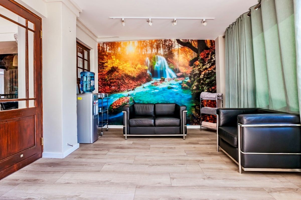 A comfortable seating area featuring wood-look flooring, track lighting, and a decorative feature wall mural.