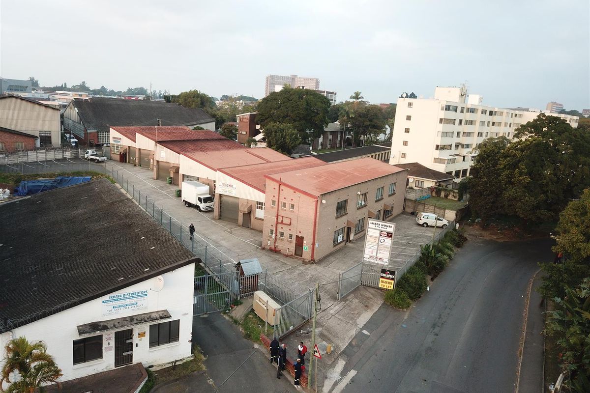 Aerial view of an industrial property complex featuring multiple warehouse units, paved yard space, and perimeter fencing with gated access.