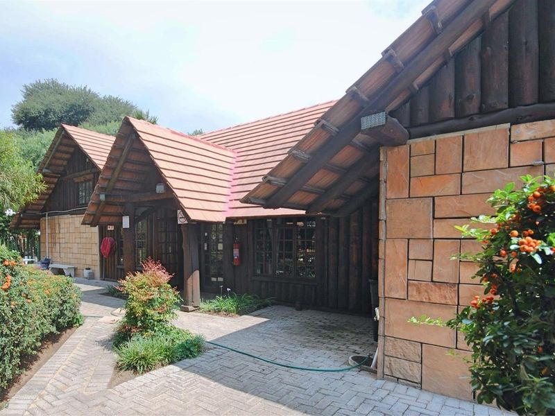 Exterior view of a rustic retail building featuring timber log cladding, stone masonry accents, and a pitched tiled roof with a paved walkway.