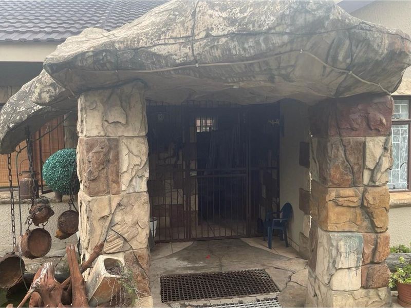 Entrance area featuring decorative rock-style stone cladding and a secure metal security gate.