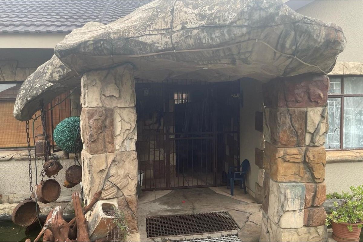 Entrance area featuring decorative rock-style stone cladding and a secure metal security gate.
